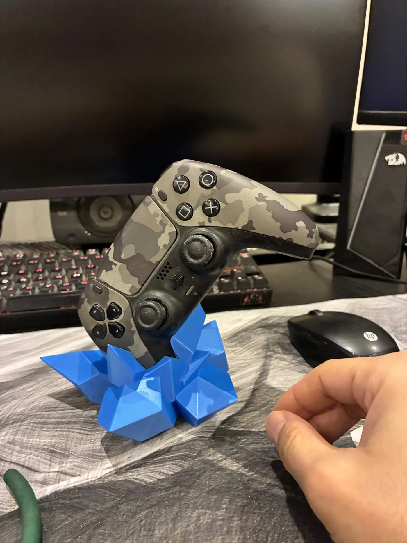 Blue faceted crystal-shaped 3D printed stand holding a camouflage game controller upright