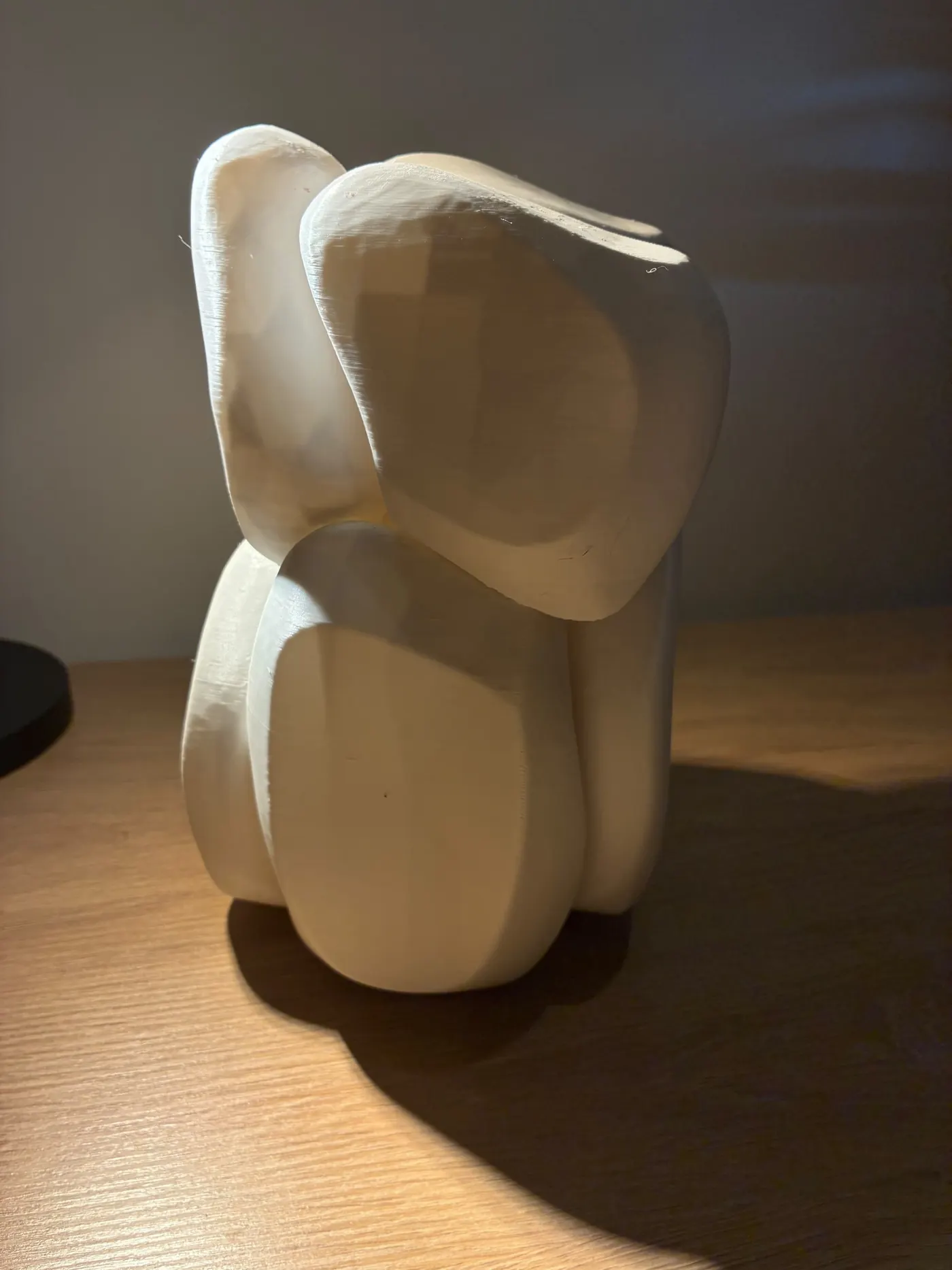 White abstract elephant sculpture made of rounded overlapping shapes on a wooden table